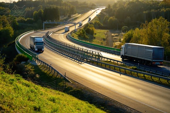 Freight trucks on a European highway at dusk.