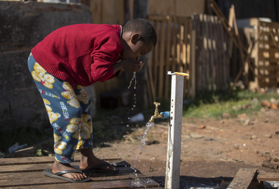 A boy brushes his teeth from a communal faucet in the Jardim Julieta squatter camp in Sao Paulo, Brazil, Thursday, July 23, 2020. The coronavirus had just hit the city when this parking lot for trucks became a favela, with dozens of shacks. Since the first wave of residents in mid-March, hundreds of families joined, with most having been evicted during the pandemic. (AP Photo/Andre Penner)