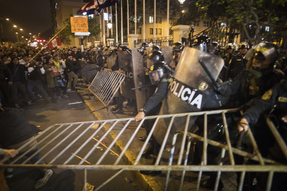 Police fight over security gates with supporters of President Martin Vizcarra outside Congress as the president's supporters try to enter the building after he disolved the body in Lima, Peru, Monday, Sept. 30, 2019. Opposition legislators in Peru defied the president's order dissolving congress and have voted to suspend him from office. (AP Photo/Rodrigo Abd)