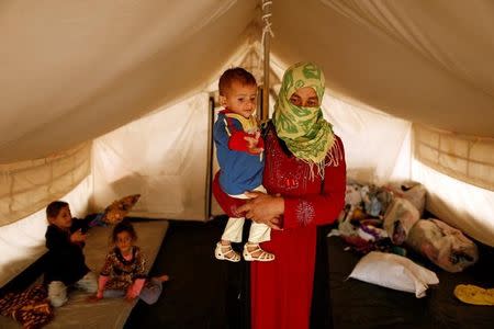 A woman who fled from Mosul carries her son Riyad, 1, who was born under Islamic State rule and has no identity documents recognised by Iraqi authorities, in Debaga refugee camp, Iraq November 10, 2016. REUTERS/Zohra Bensemra