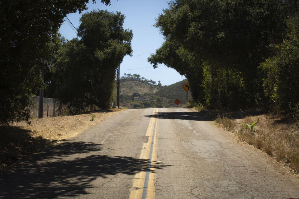 This June 28, 2019 photo shows Country Club Road, a winding, dead-end street that Lali Mitchell lives along in Harmony Grove, Calif. In the 2014 Cocos Fire, traffic snarled as residents fled their homes. A recently approved housing project along Mitchell's only escape route could put more than 400 additional cars on the road during an evacuation. If it's built, Mitchell said, staying won't be an option. (Kailey Broussard/News21 via AP)