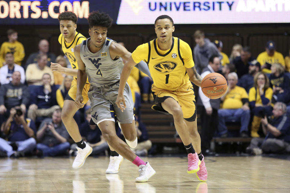 Missouri guard Xavier Pinson (1) drives it up court as he is defended by West Virginia guard Miles McBride (4) and Missouri forward Tray Jackson, behind, looks on during the first half of an NCAA college basketball game Saturday, Jan. 25, 2020, in Morgantown, W.Va. (AP Photo/Kathleen Batten)