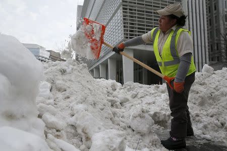 A worker shovels snow to clear a pedestrian walkway outside the World Bank in Washington January 26, 2016. REUTERS/Jonathan Ernst