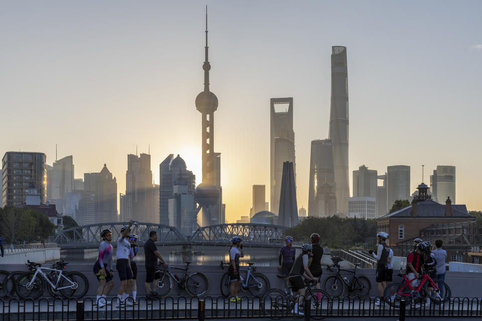 In this photo released by Xinhua News Agency, cyclists, some take selfie as they take rest against the sunrise skylines in Pudong, China's financial and commercial hub, in Shanghai, China on Friday, Nov. 3, 2023. Seeking to generate excitement around a largely lackluster economy, Chinese Premier Li Qiang on Sunday, Nov. 5, pledged to continue deepening reforms, expand free trade zones and relax market access for foreign investment. (Wang Xiang/Xinhua via AP)