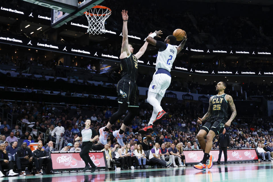 Dallas Mavericks guard Kyrie Irving (2) drives to the basket against Charlotte Hornets forward Gordon Hayward (20) as P.J. Washington looks on during the second half of an NBA basketball game in Charlotte, N.C., Sunday, March 26, 2023. Charlotte won 110-104. (AP Photo/Nell Redmond)