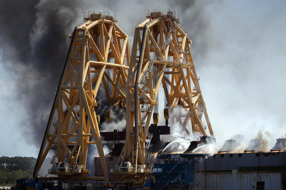 Firefighters working from the towering crane being used to dismantle the ship, hose down a fire in the overturned cargo ship Golden Ray, Friday, May 14, 2021, Brunswick, Ga. The Golden Ray had roughly 4,200 vehicles in its cargo decks when it capsized off St. Simons Island on Sept. 8, 2019. Coast Guard Petty Officer 2nd Class Michael Himes says there have been no injuries and all demolition crew members were safely evacuated. (AP Photo/Stephen B. Morton)