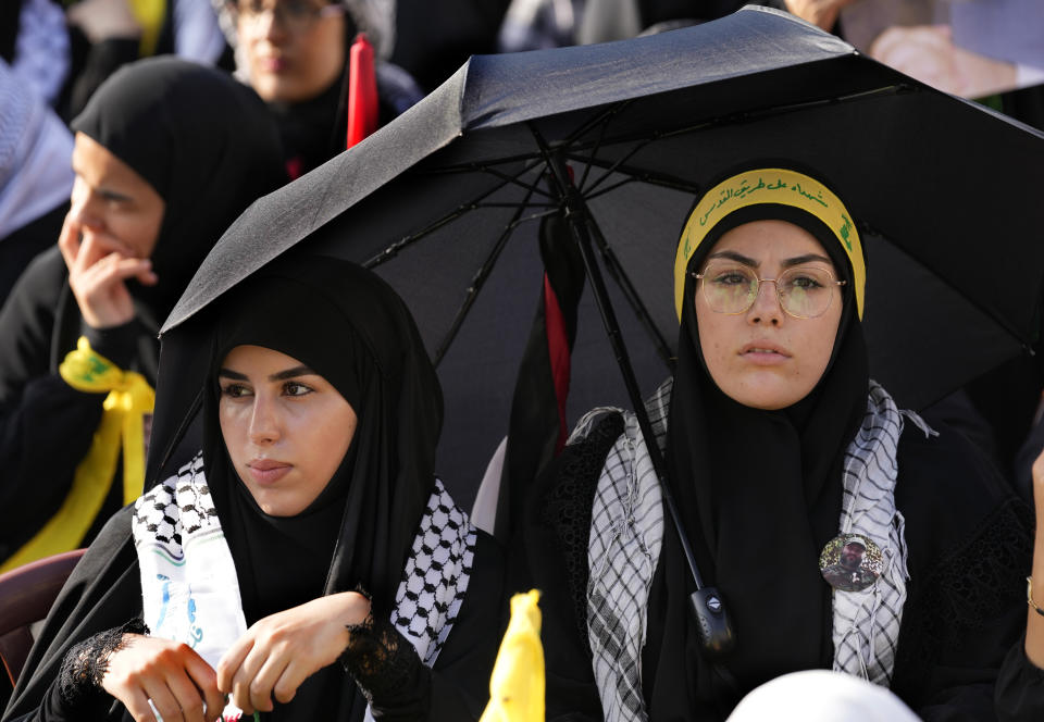 Supporters of the Iranian-backed Hezbollah group sit under an umbrella to hide from the sun, as they listen to the speech of Hezbollah leader Sayyed Hassan Nasrallah during a rally to commemorate Hezbollah fighters who were killed in South Lebanon last few weeks while fighting against the Israeli forces, in Beirut, Lebanon, Friday, Nov. 3, 2023. (AP Photo/Hussein Malla)