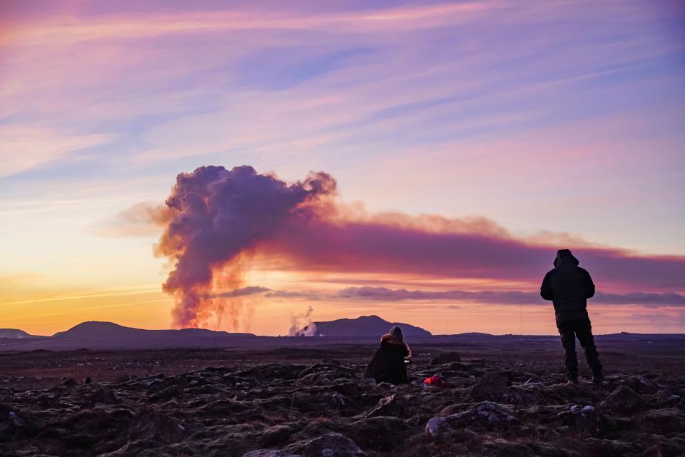 People watch from the north as the volcano erupts near Grindavík, Iceland, on Sunday (AP Photo/ Marco Di Marco)