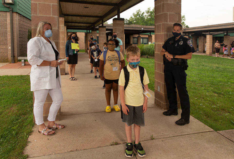 Nurse Sarah Ladd and school resource officer Kristen Tyrseck ensure kids <a href="https://time.com/5870132/schools-coronavirus/" rel="nofollow noopener" target="_blank" data-ylk="slk:keep a safe distance;elm:context_link;itc:0;sec:content-canvas" class="link ">keep a safe distance</a> apart as they enter Wesley Elementary School in Middletown, Conn., in July.<span class="copyright">Gillian Laub for TIME</span>