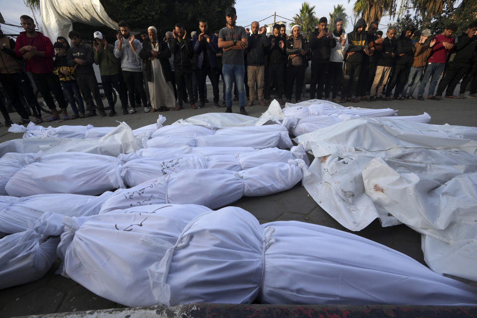 Palestinians mourn their relatives killed in the Israeli bombardment of the Gaza Strip, in front of the morgue at the hospital in Deir al Balah, Gaza Strip, on Friday, Dec. 8, 2023. (AP Photo/Adel Hana)