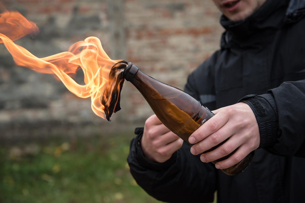 Man holding a lit Molotov cocktail