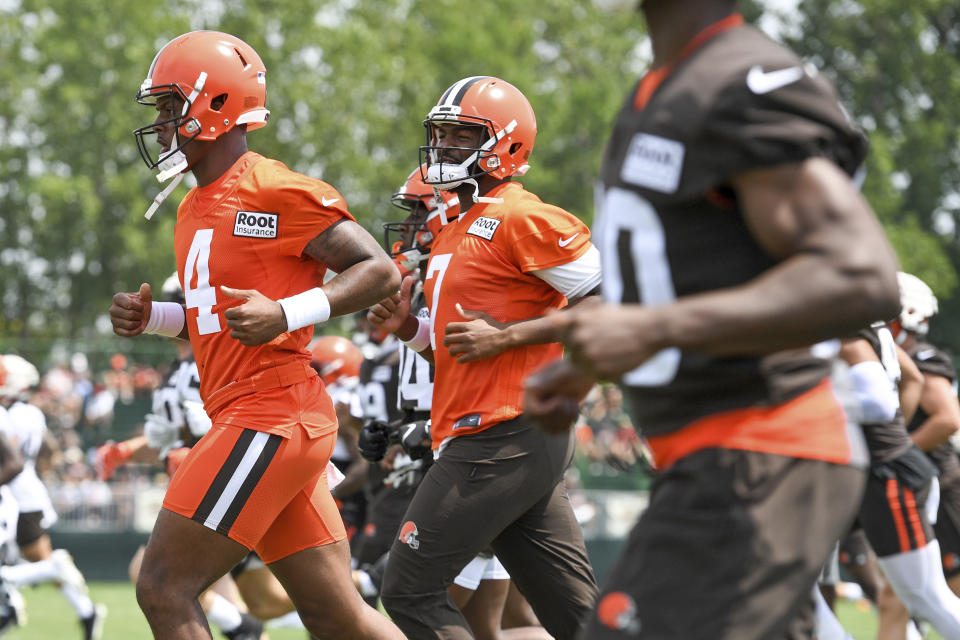 Cleveland Browns quarterbacks Deshaun Watson (4) and Jacoby Brissett (7) jog during the NFL football team's training camp, Monday, August 1, 2022, in Berea, Ohio. Watson was suspended for six games on Monday after being accused by two dozen women in Texas of sexual misconduct during massage treatments, in what a disciplinary officer said was behavior “more egregious than any before reviewed by the NFL.” (AP Photo/Nick Cammett)