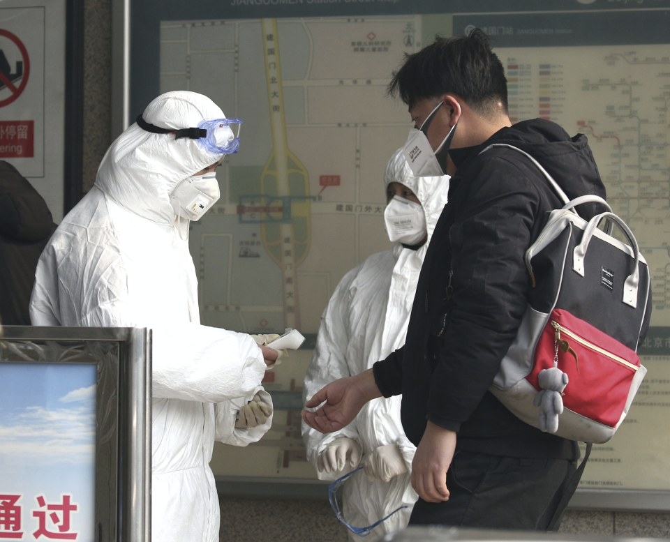 A man is seen undergoing a temperature examination by a masked physician. Source: AAP