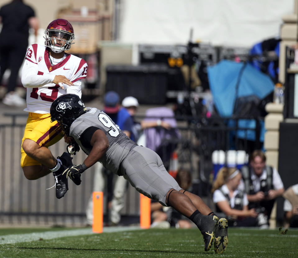 Southern California quarterback Caleb Williams, left, jumps in the air while throwing a pass before Colorado defensive lineman Bishop Thomas applies a hit in the second half of an NCAA college football game, Saturday, Sept. 30, 2023, in Boulder, Colo. (AP Photo/David Zalubowski)