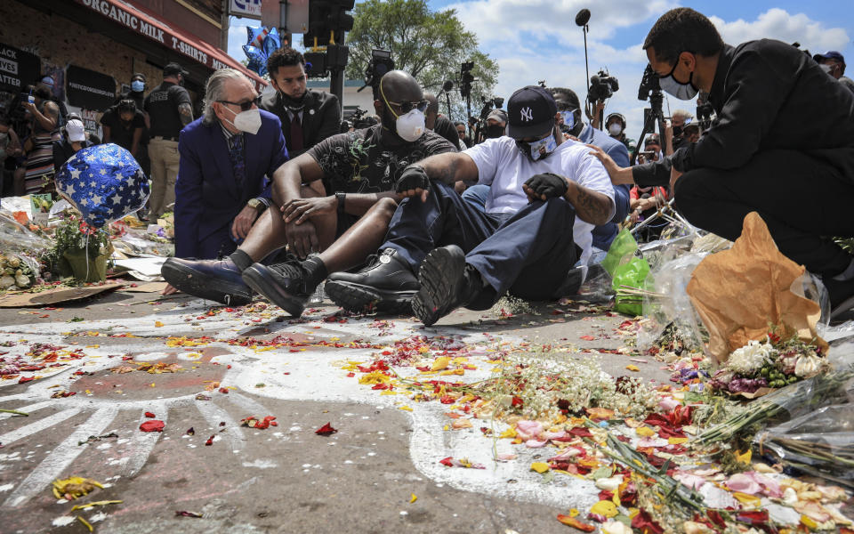 An emotional Terrence Floyd, second from right, is comforted as he sits at the spot at the intersection of 38th Street and Chicago Avenue, Minneapolis, Minn., where his brother George Floyd, encountered police and died while in their custody, Monday, June 1, 2020. (AP Photo/Bebeto Matthews)