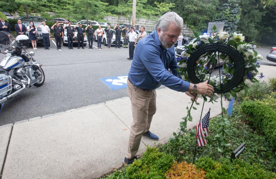 Retired Scarsdale police sergeant Tom Meaney lays a wreath at a memorial in front of Scarsdale police headquarters July 19, 2023 during a ceremony marking the 100th anniversary of the murder of Sgt. John Harrison. Sgt. Harrison was killed when he left the police desk at 4:30 am on July 19, 1923, on a report of a stolen car nearby and was fatally shot by one of the thieves less than 200 feet from headquarters.
