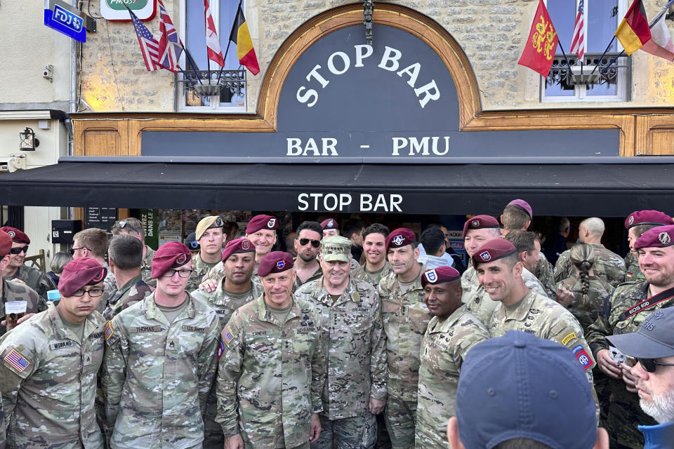 Joint Chiefs Chairman Gen. Mark Milley takes a group photo with soldiers from the 82nd Airborne Division at a bar in the town square at Sainte-Mere-Eglise in Normandy, France, June 4, 2023. The village hosts an annual D-Day celebration honoring the units who parachuted in on June 6, 1944, launching the liberation of France. This was Milley's last visit here as a soldier after a four-decade military career. He served in both the 82nd and 101st Airborne Divisions, so he spent a lot of time in the square talking to soldiers and handing out chairman's coins. (AP Photo/Tara Copp)