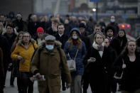 Workers walk over London Bridge towards the City of London financial district during the morning rush hour, in London, Monday, Jan. 24, 2022. The British government have asked people to return to working in offices starting Monday as they ease coronavirus restrictions. (AP Photo/Matt Dunham)