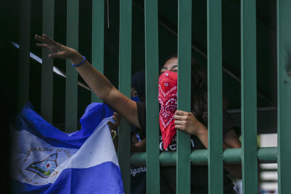 A masked student protests from behind the entrance gate of the Central American University (UCA) to demand the release of all political prisoners, on the last day of a 90-day period for releasing such prisoners as part of negotiations between the government and opposition, in Managua, Nicaragua, Tuesday, June 18, 2019. Nicaragua's government said Tuesday that it has released all prisoners detained in relation to 2018 anti-government protests, though the opposition maintains that more than 80 people it considers political prisoners are still in custody. (AP Photo/Alfredo Zuniga)