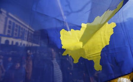 FILE PHOTO: People are pictured through Kosovo flag as they take part in celebrations of the 10th anniversary of Kosovo's independence in Pristina, Kosovo February 17, 2018. REUTERS/Ognen Teofilovski