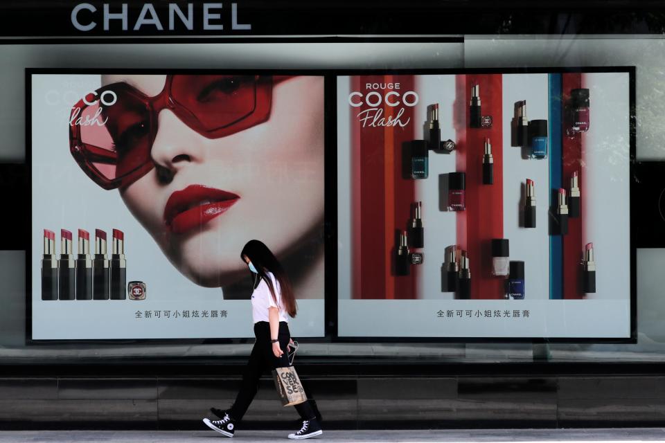 A woman wearing a face mask walks past a Chanel lipstick billboard in Beijing, May 28, 2020.