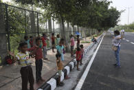 Veena Gupta, right, performs stretch exercises during a class for underprivileged children she conducts with her husband Virendra Gupta, in New Delhi, India, on Sept. 3, 2020. It all began when Veena's maid complained that with schools shut, children in her impoverished community were running amok and wasting time. The street-side classes have grown as dozens of children showed keen interest. Now the Guptas, with help from their driver, teach three different groups three times a week, morning and evening. As most schools in India remain shut since late March when the country imposed a nationwide lockdown to curb the spread of COVID-19, many switched to digital learning and taking classes online. (AP Photo/Manish Swarup)