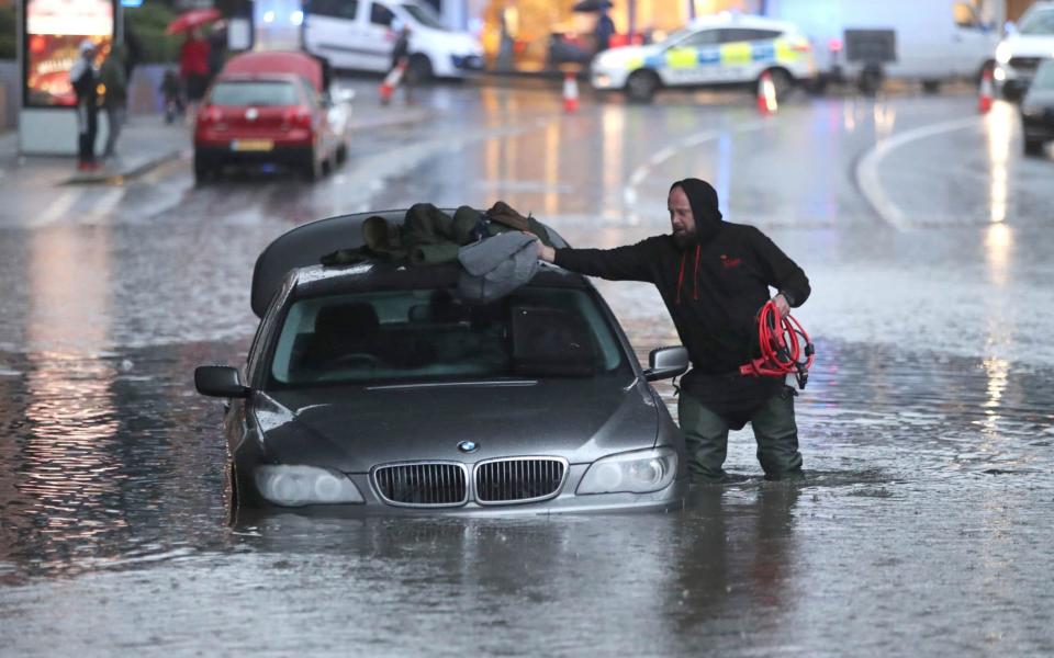 A man with car in a flooded street Sheffield - PA