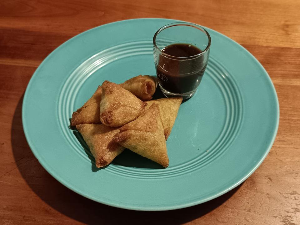 Samosas on a blue-green plate with a dipping sauce