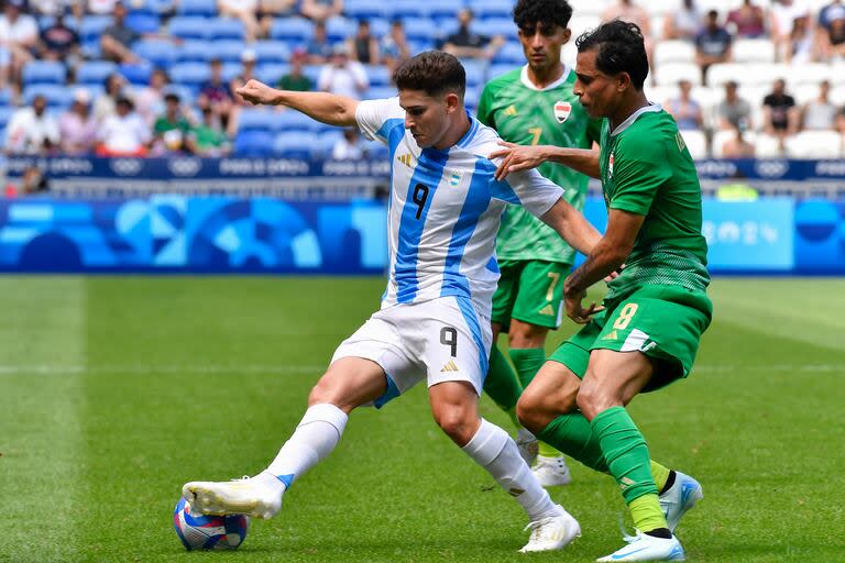 Julián Álvarez cubre la pelota ante un defensor de Irak