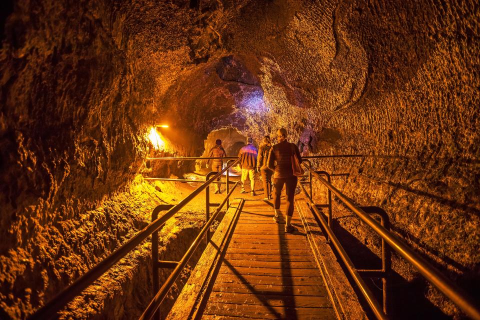 Visitors walk through Nāhuku lava tube at Hawaii Volcanoes National Park.