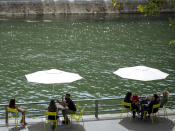 ARCHIVO - En esta imagen del 28 de julio de 2020, gente sentada junto al río Sena en París. Un brote de coronavirus en una zona turística de Francia se está convirtiendo en un ejemplo de manual de cómo el virus enfrenta generaciones entre sí. En una semana se han descubierto 72 casos, la mayoría en veraneantes y trabajadores de temporada entre 18 y 25 años. (AP Foto/Kamil Zihnioglu, Archivo)