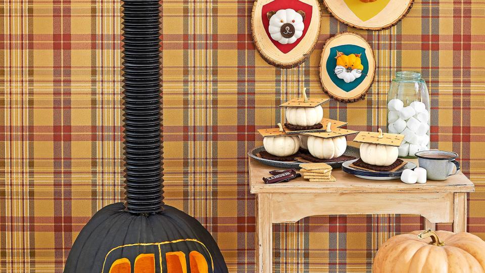 cozy cabin scene with wood burning stove, hunting trophy plaques and smores all made from pumpkins, plaid wallpaper backdrop