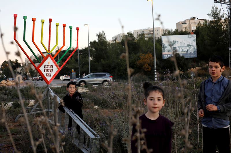 Children from the Shternefeld family stand next to a hanukkiyah, a candlestick with nine branches that is lit to mark Hanukkah, the 8-day Jewish Festival of Lights, in Kiryat Ye'arim, Israel