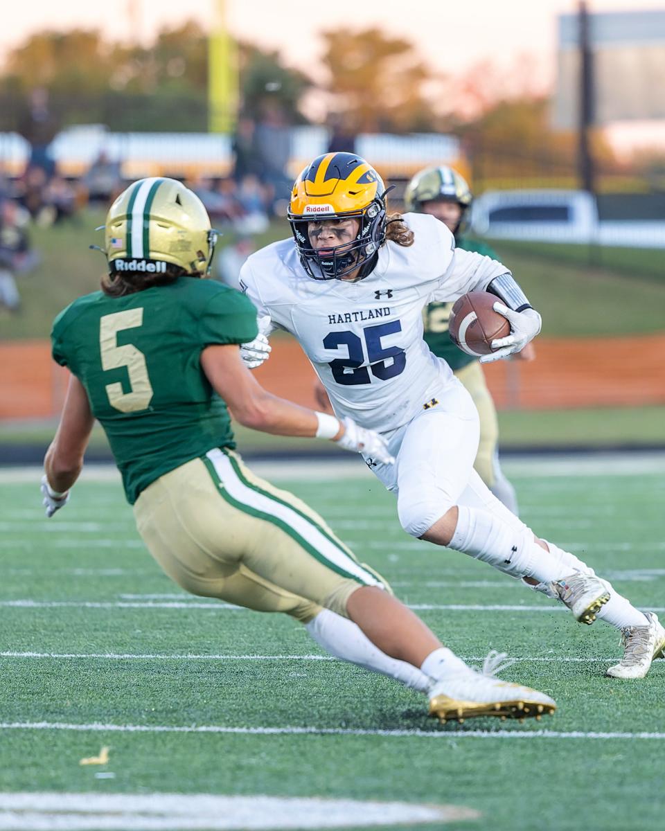 Hartland's Nevan Anderer (25) runs the ball while defended by Howell's Logan Porter (5) during the Eagles' 33-13 victory on Friday, Sept. 30, 2022.