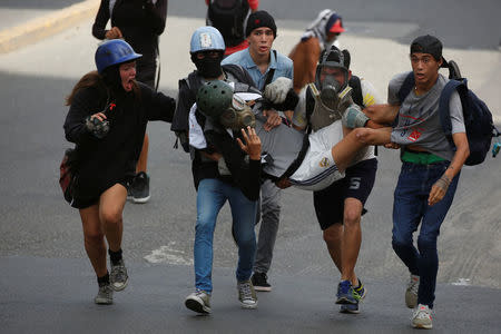 An injured demonstrator is helped by fellow protesters during clashes with riot security forces at a rally against Venezuelan President Nicolas Maduro's government in Caracas. REUTERS/Carlos Garcia Rawlins