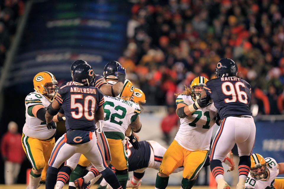 Green Bay Packers quarterback Aaron Rodgers (12) gets away from Chicago Bears defensive end Julius Peppers (90) after Peppers is deflected by Packers fullback John Kuhn (30). This gave Rodgers time to scramble and unload a 48-yard touchdown pass to wide receiver Randall Cobb during Green Bay's 33-28 win Dec. 19, 2013, at Soldier Field in Chicago.