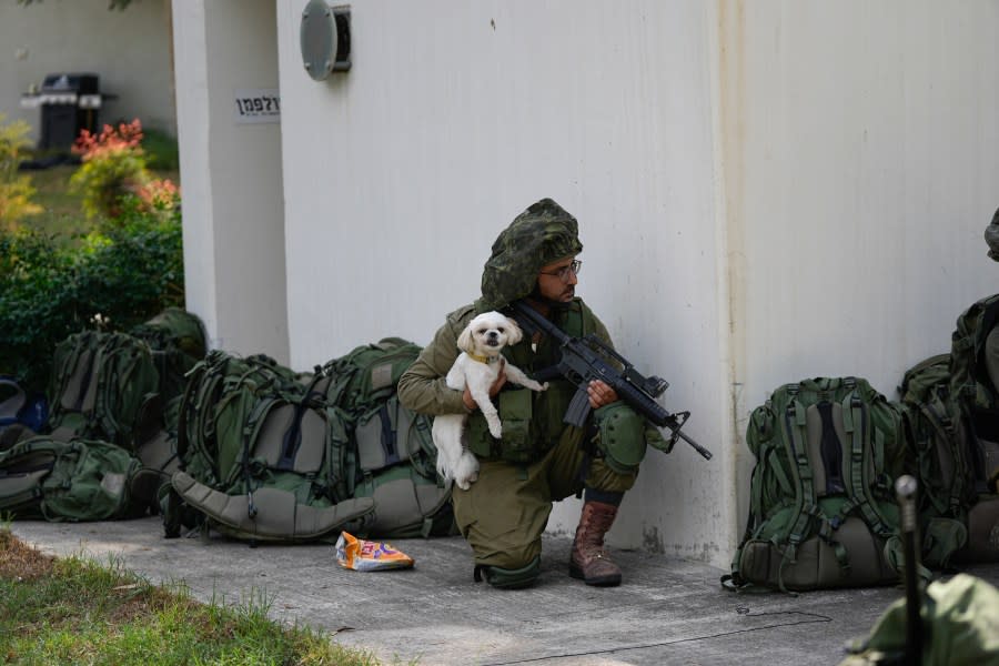 An Israeli soldier holds a dog in kibbutz Kfar Azza on Tuesday, Oct. 10, 2023. Hamas militants overran Kfar Azza on Saturday, where many Israelis were killed and taken captive. (AP Photo/Ohad Zwigenberg)