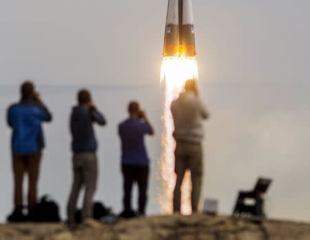 Photographers take pictures as the Soyuz TMA-18M spacecraft carrying the crew of Aidyn Aimbetov of Kazakhstan, Sergei Volkov of Russia and Andreas Mogensen of Denmark blasts off from the launch pad at the Baikonur cosmodrome, Kazakhstan, September 2, 2015. REUTERS/Shamil Zhumatov