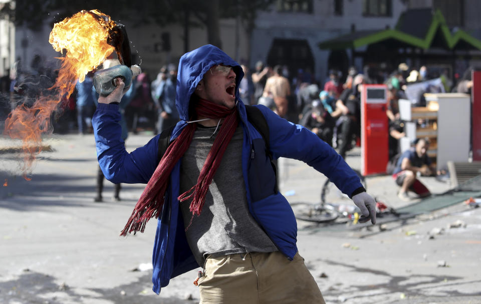An anti-government protester throws a firebomb at police amid a march by students and union members in Santiago, Chile, Monday, Oct. 21, 2019. Protesters defied an emergency decree and confronted police in Chile’s capital on Monday, continuing disturbances that have left at least 11 dead and led the president to say the country is “at war.” (AP Photo/Miguel Arenas)