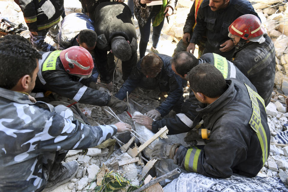 In this photo released by the Syrian official news agency SANA, people and rescue workers search for victims under the rubble of a destroyed building where, according to SANA, the five-story building collapsed early Saturday, Feb. 2, 2019 killing most of those who were inside and only one person was rescued alive, in the northern city of Aleppo, Syria. SANA said that a building damaged during years of war in the northern city of Aleppo has collapsed killing 11 people. (SANA via AP)