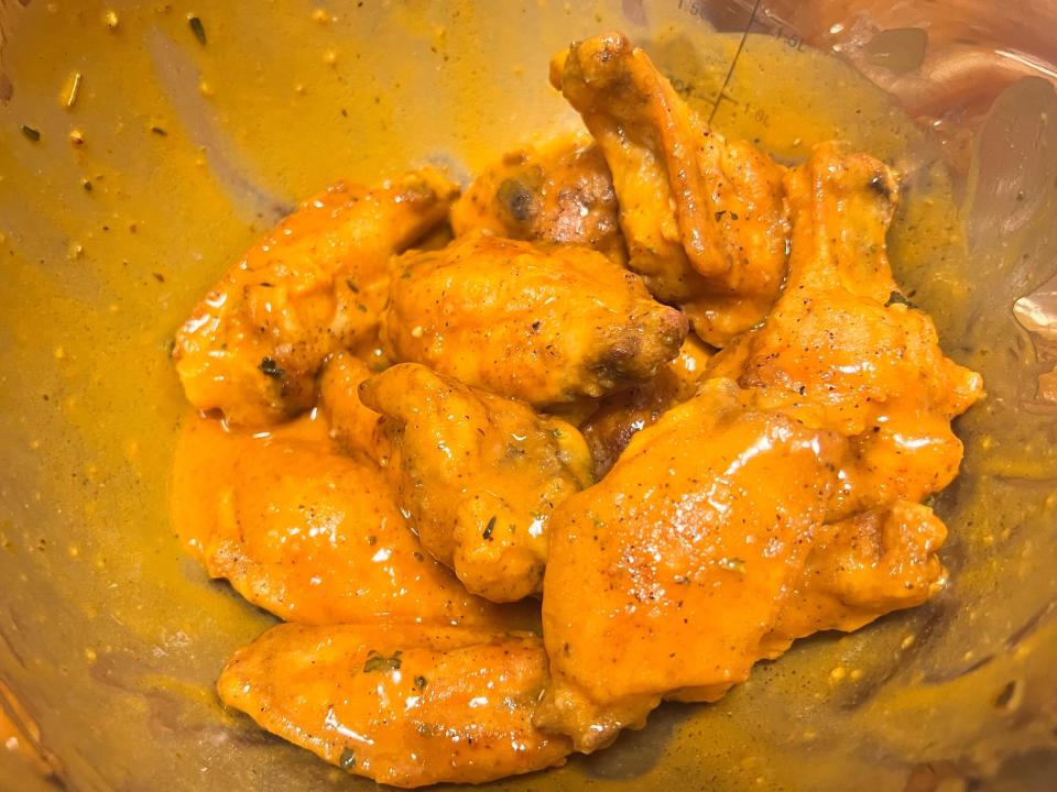 Chicken wings tossed with buffalo sauce in bowl