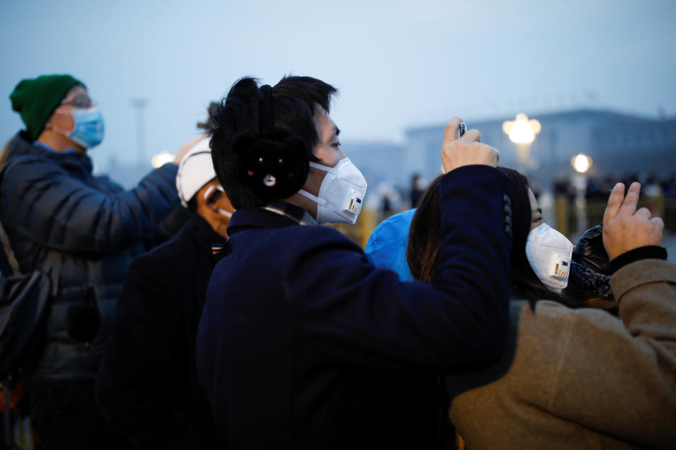 People wearing face masks use their cellphones at the Tiananmen Square, as the country is hit by an outbreak of the new coronavirus, in Beijing, China January 27, 2020. REUTERS/Carlos Garcia Rawlins