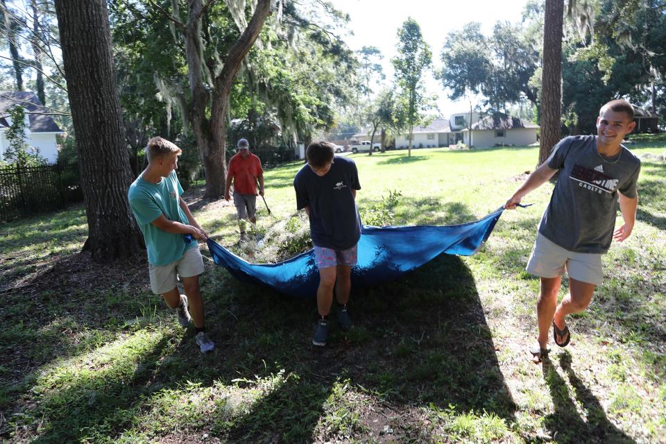 Benedictine cadets Kaleb Roberts, Grant Pilgrim, and Sam Lecates help Jason Pilgrim (back) clean up the yard of his Walthour Road home on Thursday, August 31, 2023.