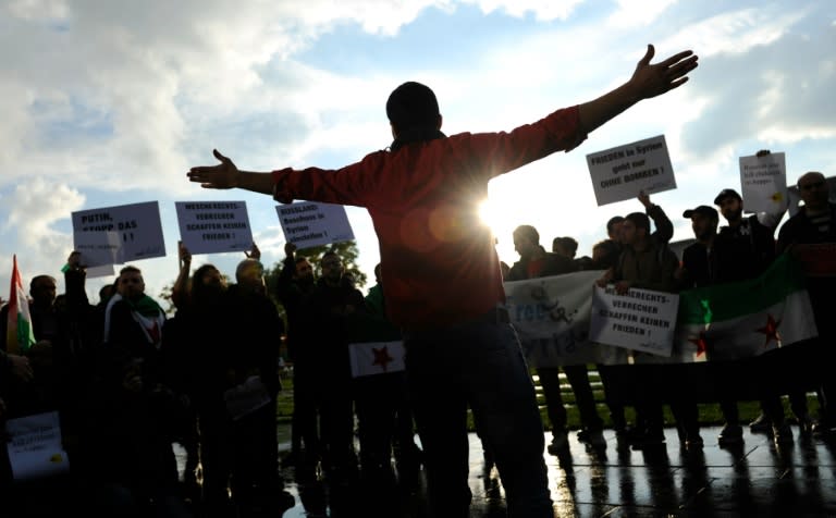 Protesters hold signs during a demonstration in Berlin against the bombing of Aleppo