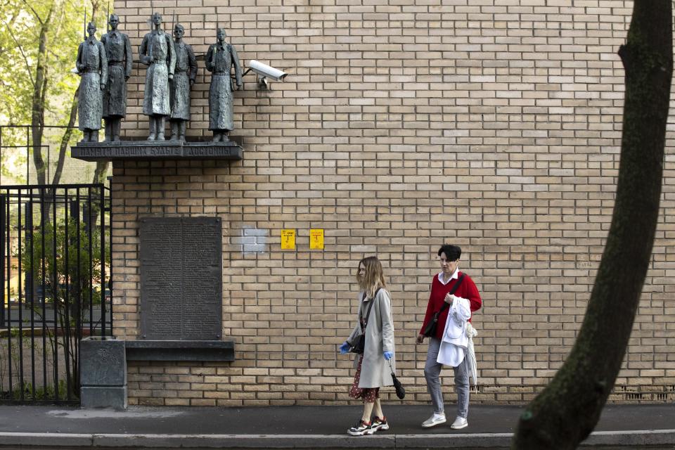 Dos jóvenes pasan junto a un monumento de Moscú dedicado a los menores que fallecieron combatiendo en la Segunda Guerra Mundial. Foto del 5 de mayo del 2020. (AP Photo/Alexander Zemlianichenko)