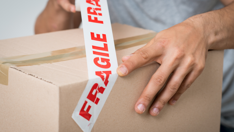 Man wraps box in fragile tape - Francesco Ridolfi/iStockphoto