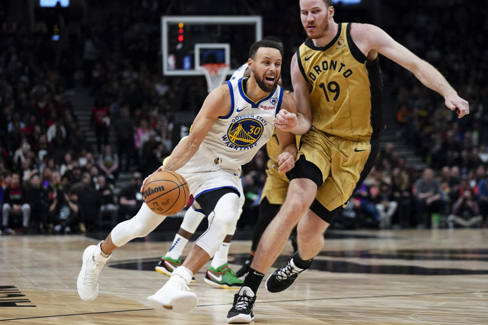 Golden State Warriors guard Stephen Curry (30) drives past Toronto Raptors centre Jakob Poeltl (19) during the first half of an NBA basketball game Friday, March 1, 2024, in Toronto. (Arlyn McAdorey/The Canadian Press via AP)