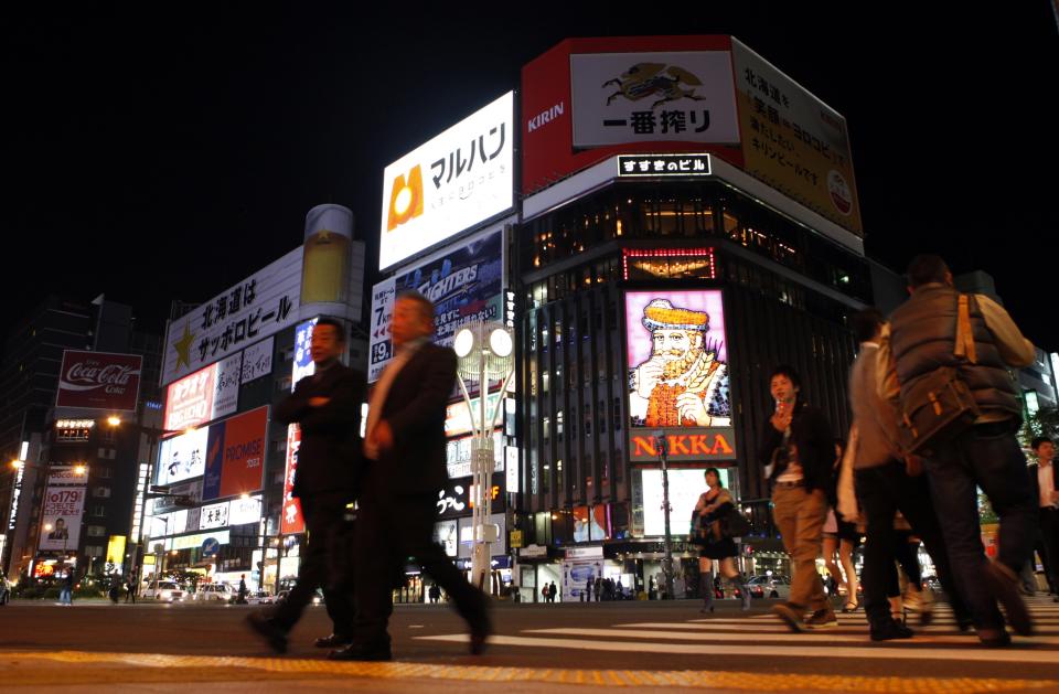 REFILE - CORRECTING SPELLING ERROR IN SECOND SENTENCE People walk along a pedestrians' crossing at Susukino shopping and amusement district in Sapporo, on Japan's northern island of Hokkaido October 9, 2013. When a Tokyo-based investment manager set out to win business from a pension fund in northern Japan, the cost included dozens of nights drinking at Club Godfather, a discreet watering hole with a $200 cover charge and kimono-clad hostesses. Takahama, now 71, was treated to more than 50 nights out at the club in Sapporo as KTOs Capital Partners, a hedge fund, lobbied for a share of the $245 million pension fund he helped oversee as its chairman, prosecutors say. Takahama was sentenced to 18 months in prison on Thursday, a sentence that was suspended for three years, after he pleaded guilty to accepting a bribe. While viewed as an extreme case, the prosecution of Takahama has been watched as a sign of the increasing willingness of Japanese regulators and prosecutors to crack down on what they see as the corrupting influence of entertainment. Picture taken October 9, 2013. REUTERS/Nathan Layne (JAPAN - Tags: BUSINESS CRIME LAW SOCIETY)