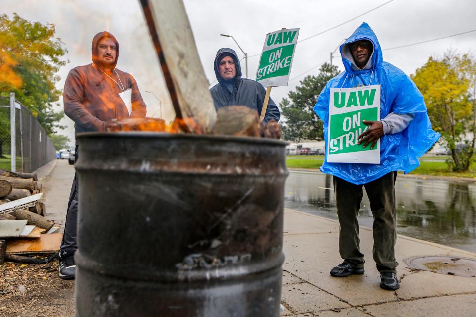 UAW autoworkers Davor Janceski, 41, of Macomb; Edward LeBlanc 48, of Lincoln Park and Martin Jackson, 68, of Detroit  keep warm near a burn barrel while they strike in the rain in front of the General Motors Detroit-Hamtramck assembly plant in Hamtramck, Mich. on Wednesday, Oct. 16, 2019. General Motors and the UAW reached a proposed tentative agreement on a new contract Wednesday, the 31st day of a nationwide strike. 