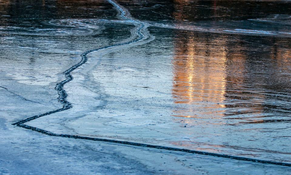 An ice fissure meanders on the surface of the Manitowoc River near the 8th St. bridge, Friday, January 21, 2022, in Manitowoc, Wis.